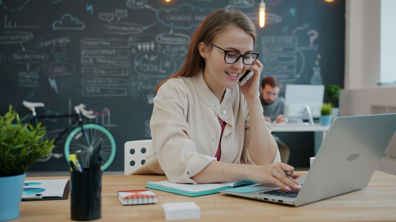 A business owner smiling on a phone call at her desk