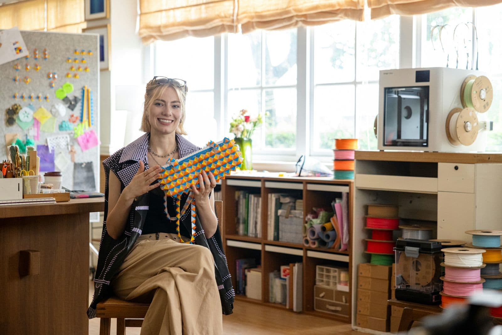 A small business owner smiling in her workshop, holding one of her handmade pieces